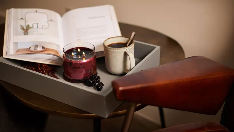 Coffee table books styled as housewarming gifts on a warm neutral coffee table with candle and ceramic decor