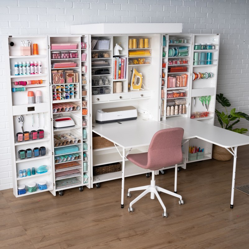 Craft desk with drawers and shelves in a small room, organized with art supplies and tools