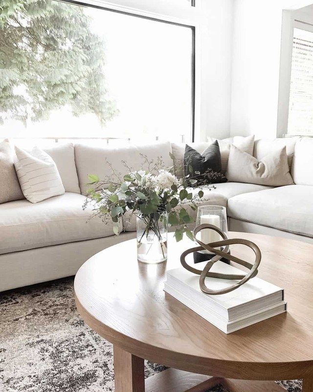 A stack of affordable coffee table books styled on a living room table with neutral decor accents
