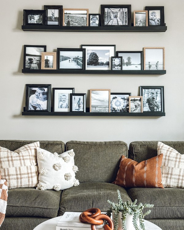 Picture ledges hung in a balanced arrangement above a sofa with even spacing and aligned artwork
