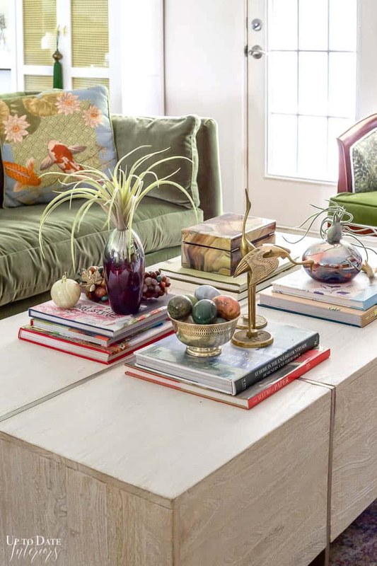 Neutral shelf with stacked coffee table books, small vase, and framed art for styling reference