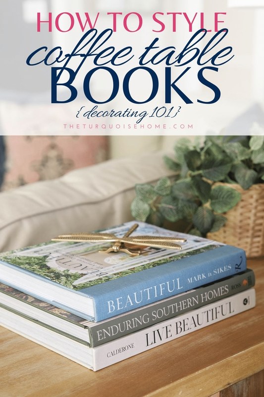 Stacked coffee table books beside a sofa with varied cover sizes, colors, and subjects