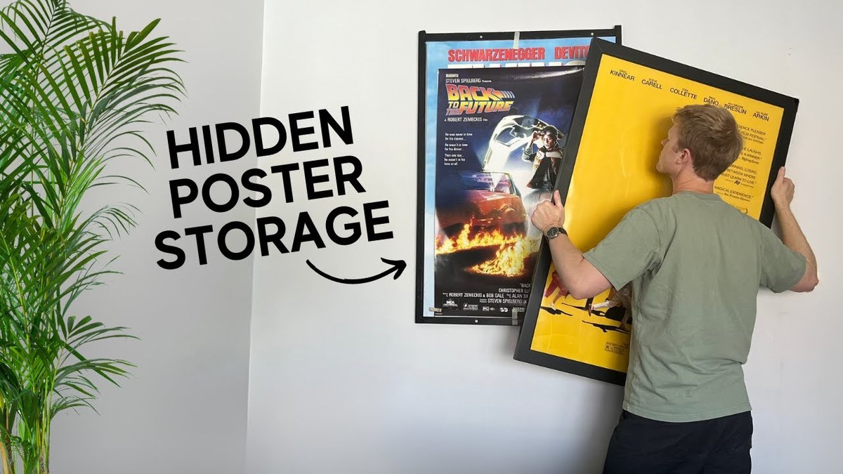 Framed poster held upright with taped glass and padded corners during transport