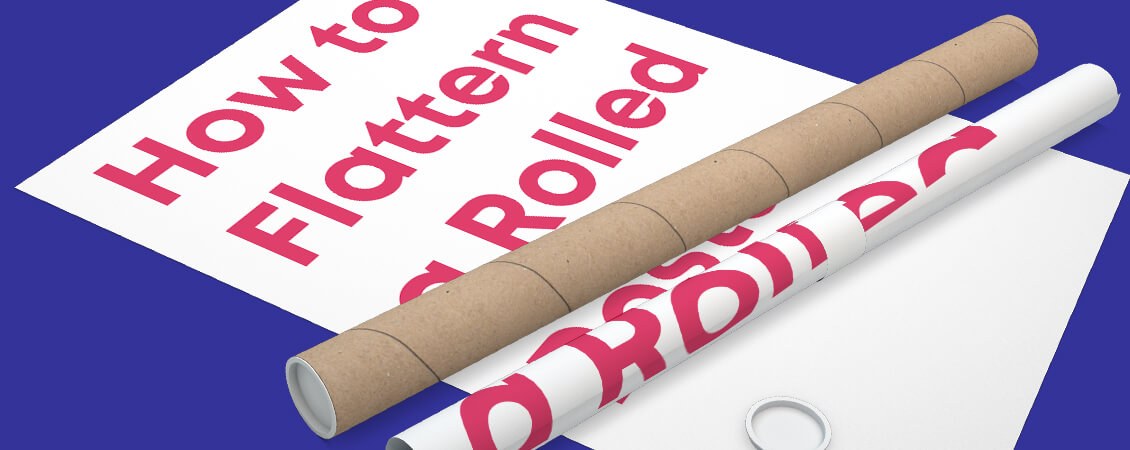 A person stacking heavy books unevenly on a rolled poster, causing the paper to crease and curl