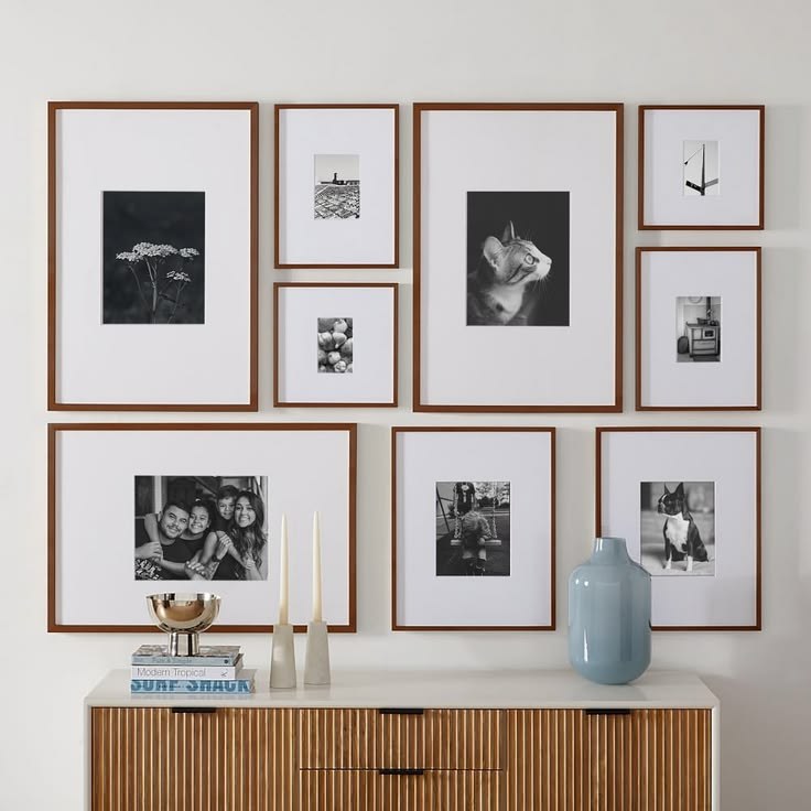 A gallery wall mixing white picture frames and light wood picture frames in a bright living room