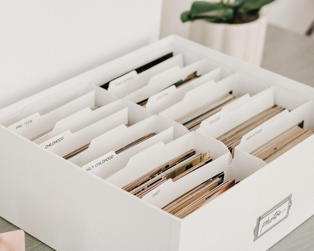 Labeled archival storage boxes arranged on shelves, showing a step-by-step home organization system.