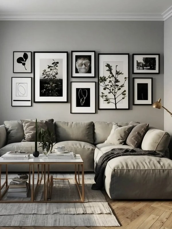 Minimalist gallery wall with mixed black and wood frames above a neutral-toned sofa in a bright living room
