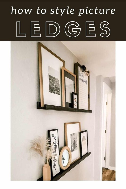 Close-up of a wooden picture ledge mounted on a wall holding two framed pictures